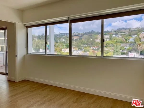 an empty room with wooden floor and a large window