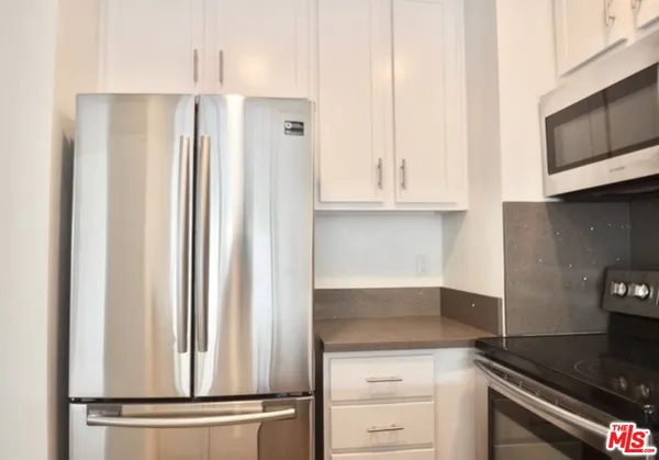 a kitchen with granite countertop white cabinets and stainless steel appliances