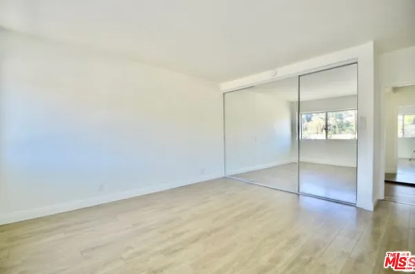 an empty room with wooden floor and mirror
