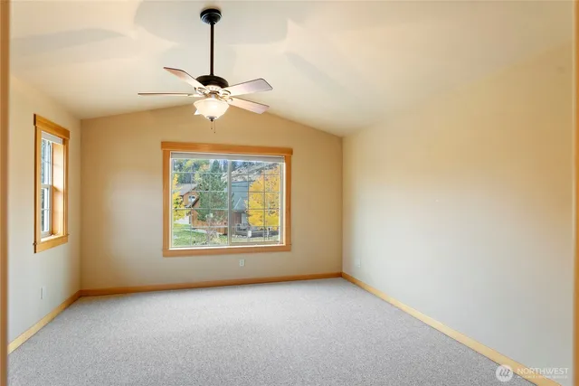 an empty room with windows and ceiling fan