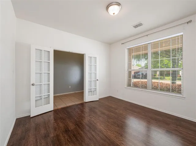 an empty room with wooden floor and windows