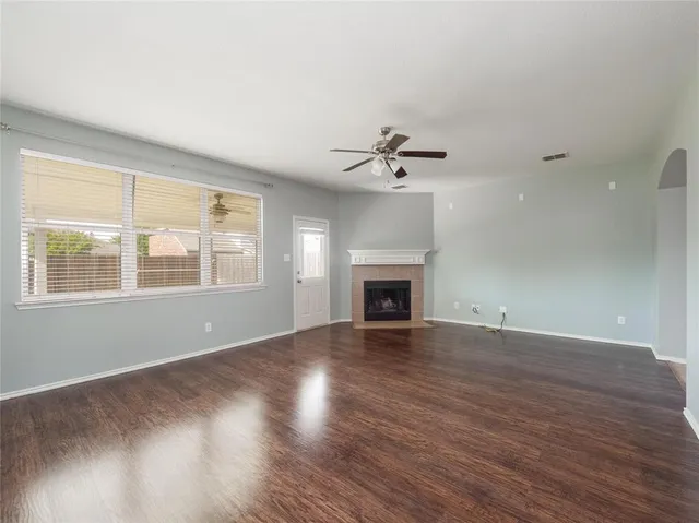an empty room with wooden floor chandelier and windows
