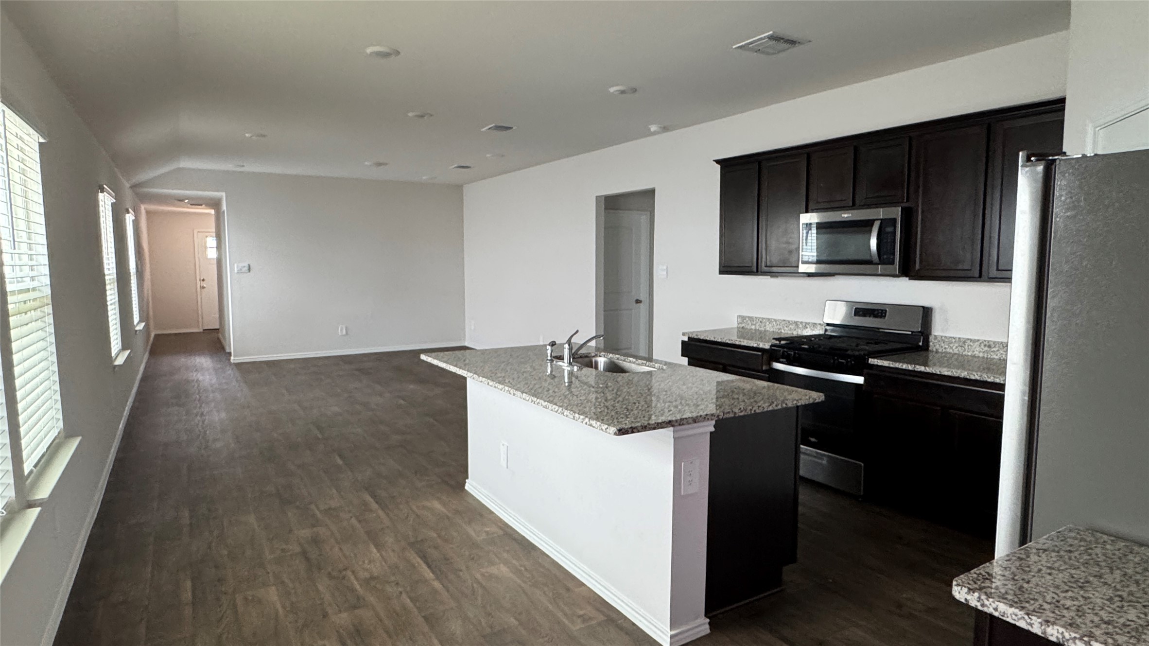 408 Frogmore Loop Kyle, TX 78640 - Photo 7 of 32 An open-concept living area boasts a modern kitchen with an island sink, sleek dark cabinetry, and integrated appliances.