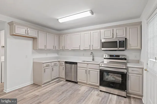 a kitchen with cabinets stainless steel appliances and wooden floor