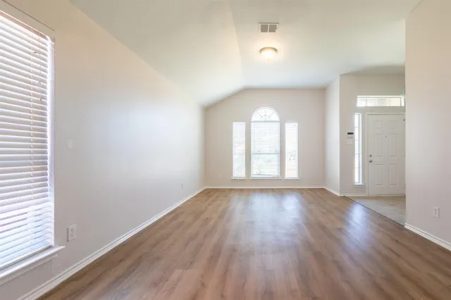 an empty room with wooden floor and windows