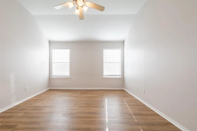 an empty room with wooden floor and windows