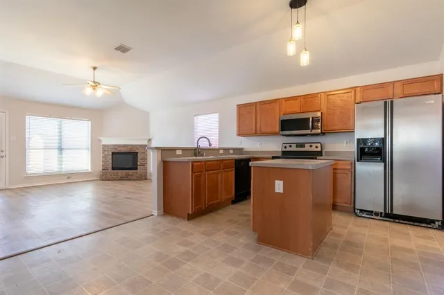 a kitchen with stainless steel appliances a refrigerator a stove a sink a microwave a dining table and chairs with wooden floor