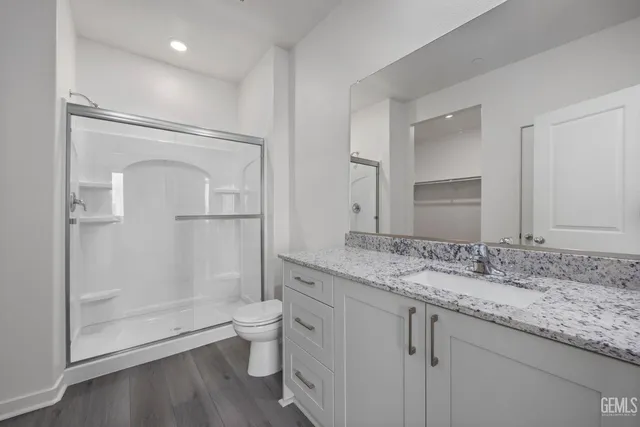 a bathroom with a granite countertop sink a toilet and shower