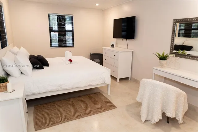 a bedroom with a bed a flat tv screen and a bookshelf