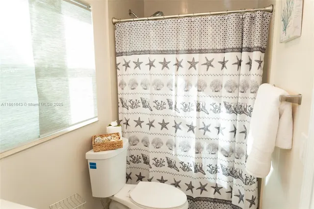 a bathroom with a toilet and shower curtain