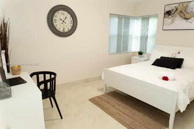 a white bed sitting in a bedroom next to a window