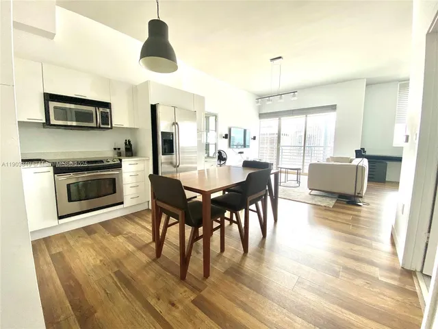 a dining room with wooden floor a chandelier a glass table and chairs