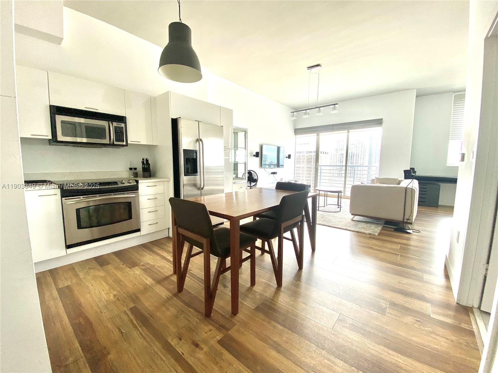 133 Northeast 2nd Avenue, Unit 2904 Miami, FL 33132 - Photo 5 of 11 a dining room with wooden floor a chandelier a glass table and chairs