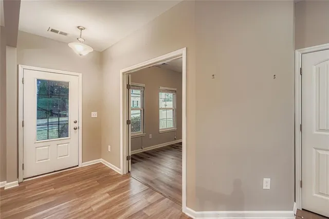 a view of an empty room with wooden floor and a window