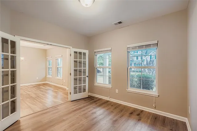an empty room with wooden floor and windows