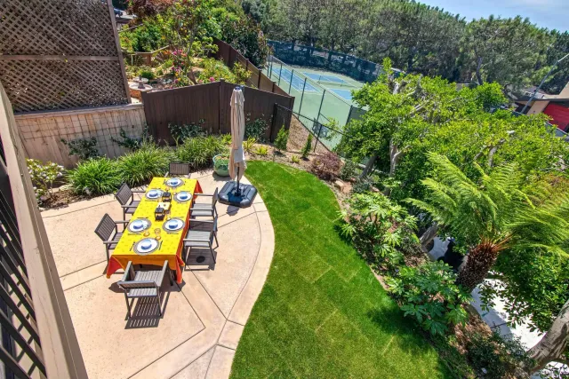 a view of a chair and table in backyard with potted plants