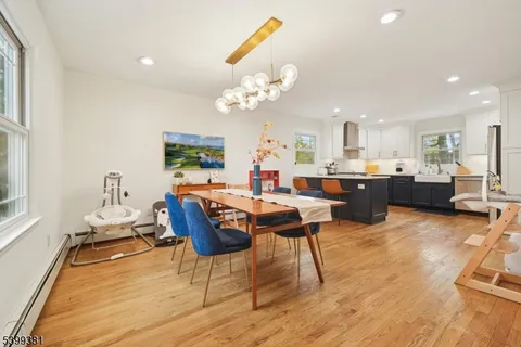 a kitchen with stainless steel appliances granite countertop a stove a sink a refrigerator white cabinets and wooden floor