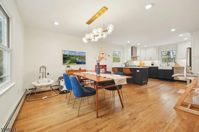 a kitchen with stainless steel appliances granite countertop a stove a sink a refrigerator white cabinets and wooden floor