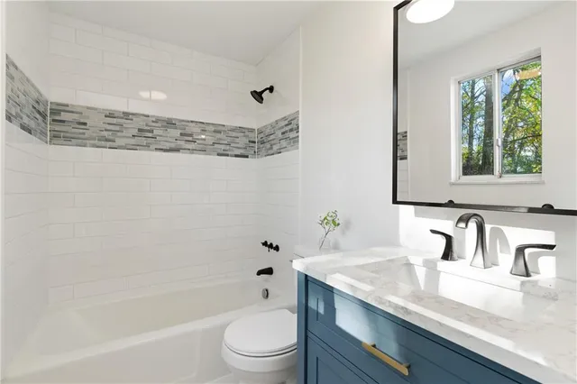 a bathroom with a granite countertop sink a toilet a mirror and bathtub