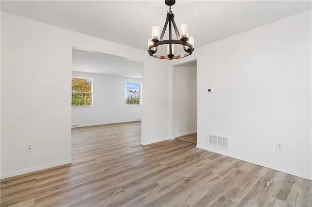 a view of a room with wooden floor ceiling fan and window
