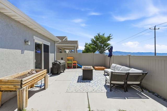 1175 Silver Hollow Road Syracuse, UT 84075 - Photo 31 of 34 Expansive concrete patio with a privacy fence, sliding glass door access, and a mountain backdrop