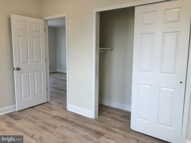 an empty room with wooden floor & closet area