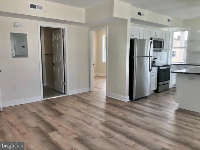 a view of a kitchen with refrigerator and wooden floor