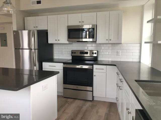 a kitchen with granite countertop a refrigerator stove and microwave