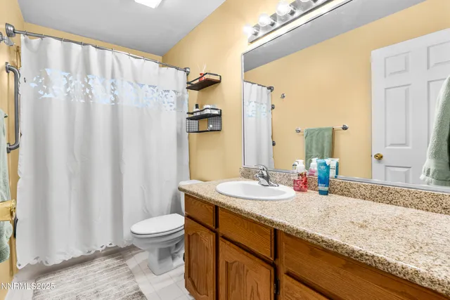 a bathroom with a granite countertop sink toilet and a mirror
