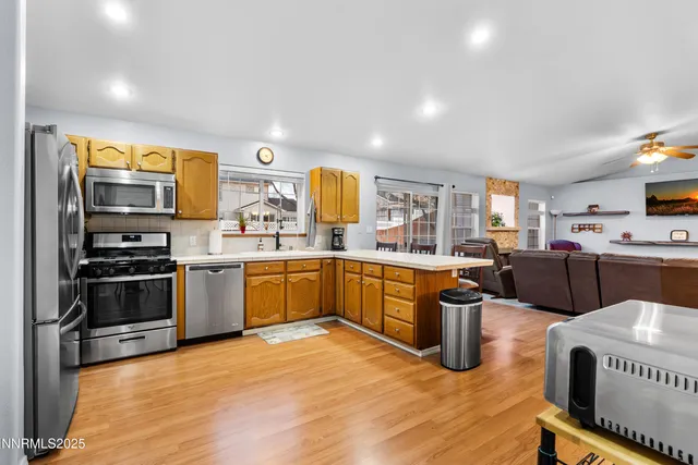 a kitchen with stainless steel appliances a stove a sink dishwasher a oven with white cabinets and wooden floor