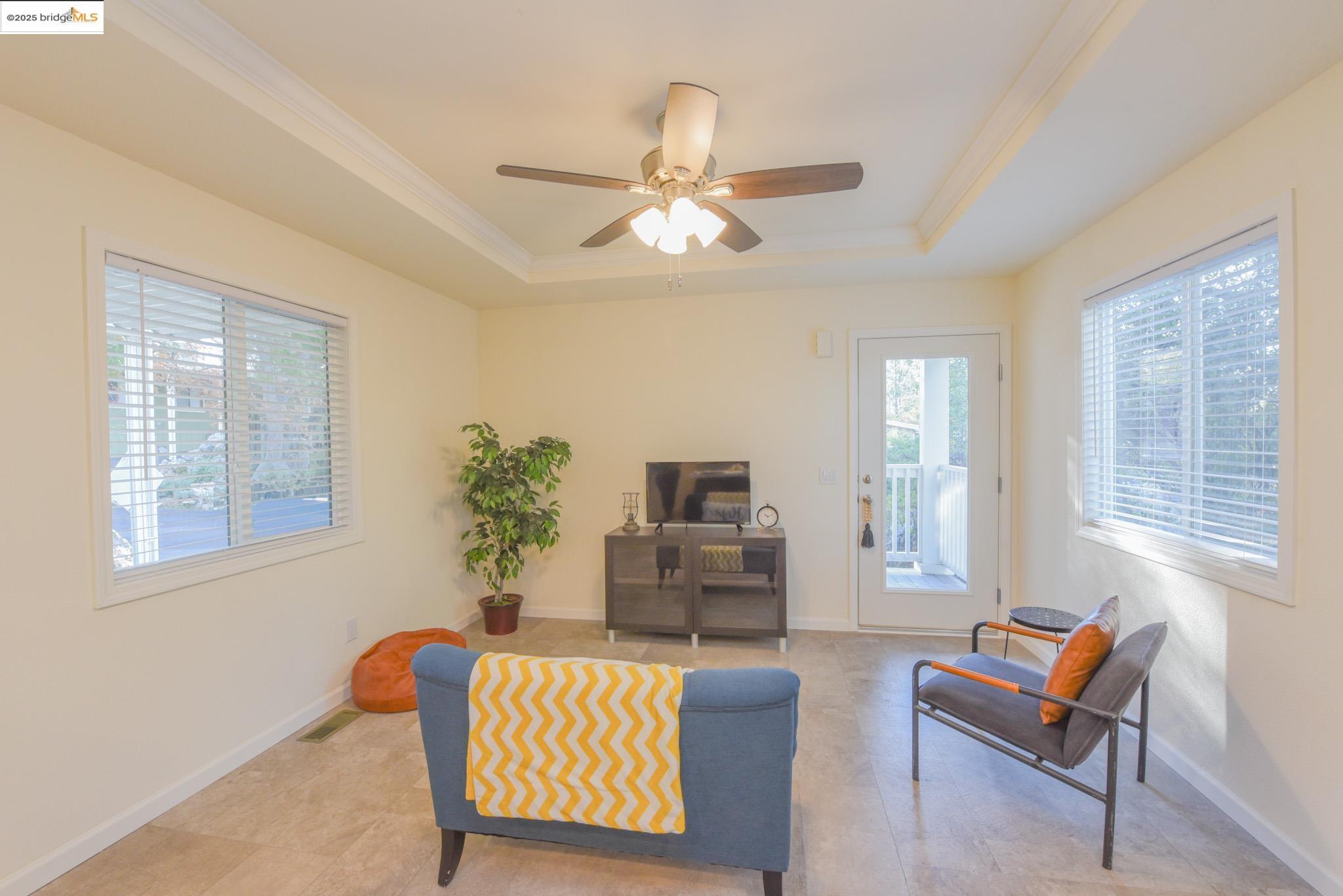 10956 Green Street Columbia, CA 95310 - Photo 7 of 45 Living area featuring a tray ceiling, a ceiling fan, and crown molding