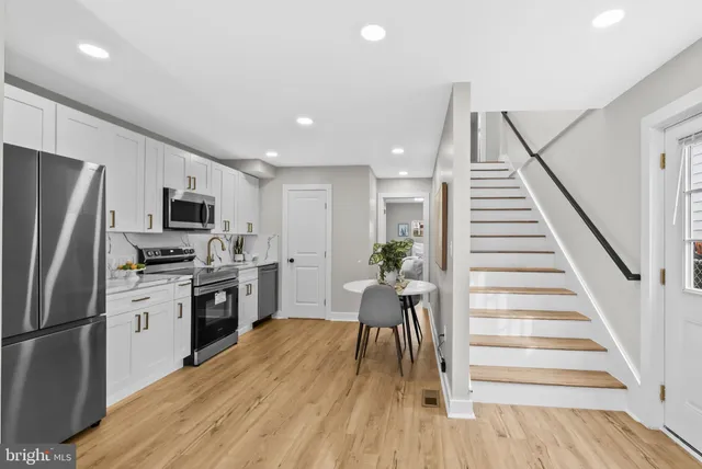 a kitchen with white cabinets stainless steel appliances and wooden floor