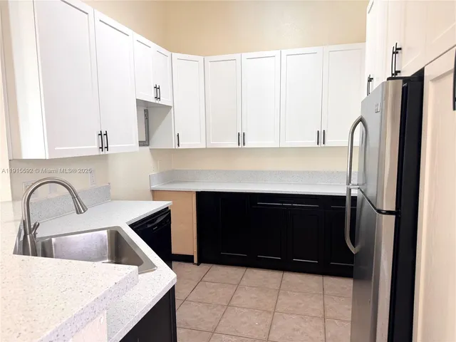 a kitchen with a refrigerator and white cabinets