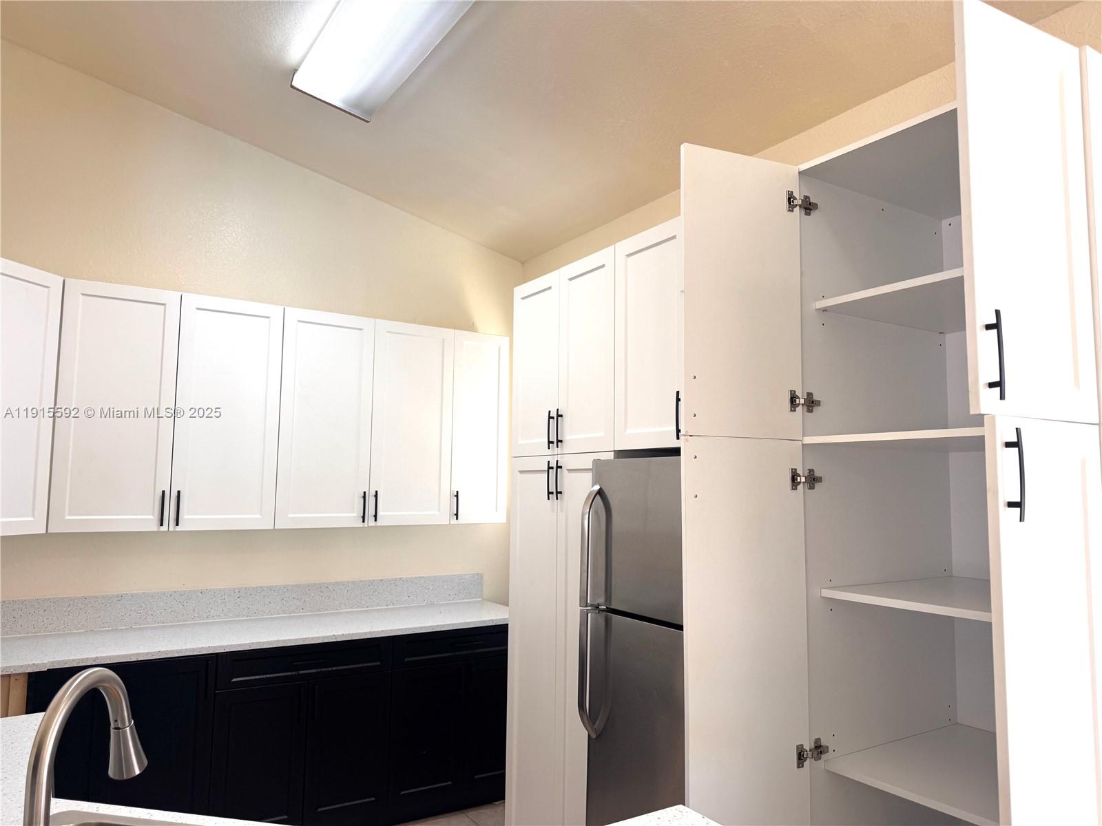3725 Northeast 23rd Court Homestead, FL 33033 - Photo 12 of 25 a kitchen with a refrigerator and white cabinets