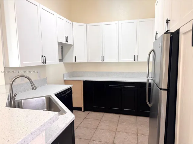 a kitchen with a refrigerator and white cabinets