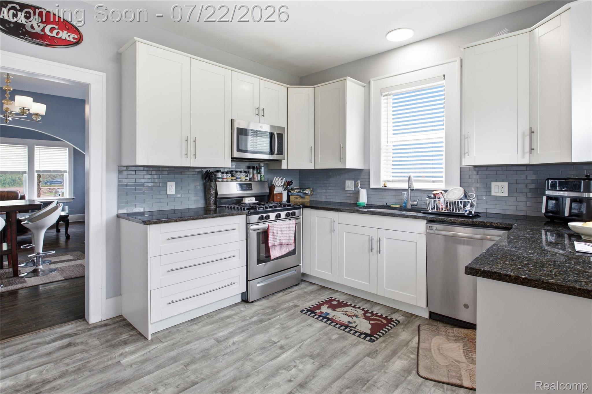 32127 Utica Road Fraser, MI 48026 - Photo 11 of 43 Modern kitchen featuring white cabinetry, dark stone countertops, stainless steel appliances, and wood-finish flooring