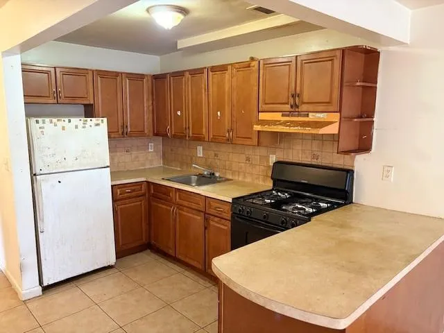 a kitchen with a refrigerator a stove top oven and cabinets