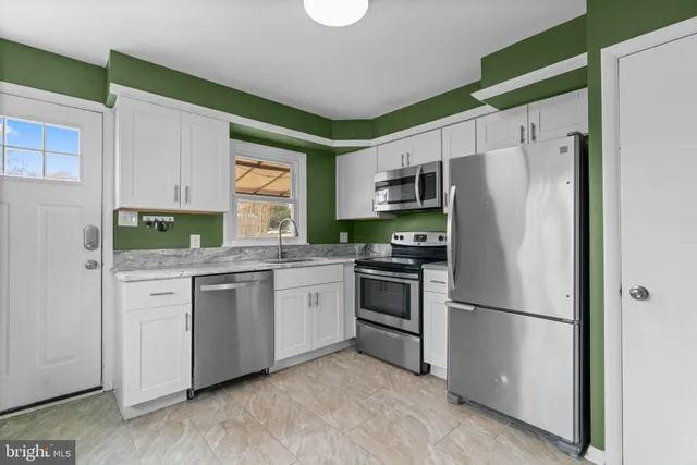 a kitchen with granite countertop stainless steel appliances a refrigerator sink and microwave