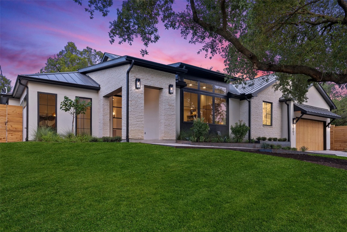 1001 Bluebonnet Lane Austin, TX 78704 - Photo 1 of 1 Modern home featuring brick siding, an attached garage, a standing seam roof, a metal roof, and driveway