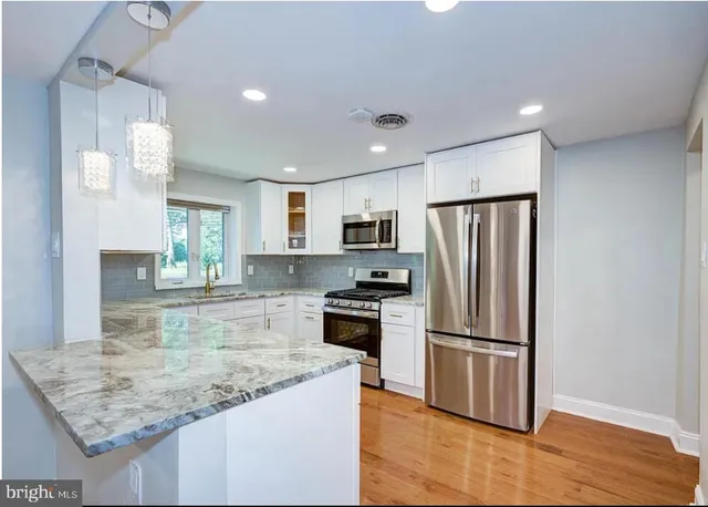 a kitchen with kitchen island a counter top space cabinets and stainless steel appliances