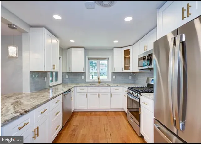 a large kitchen with stainless steel appliances granite countertop a refrigerator and a sink