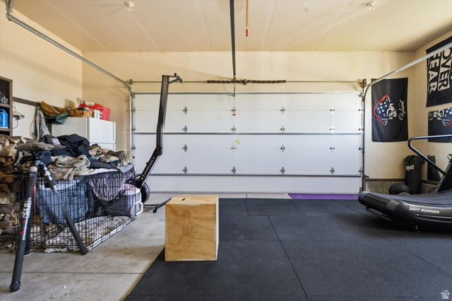 1634 West Arimo Road Arimo, ID 83214 - Photo 24 of 89 Garage space featuring a roll-up garage door, painted walls, overhead lighting, and a partial rubber flooring system