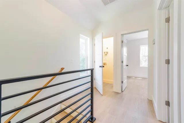 a view of a hallway with wooden floor and bathroom