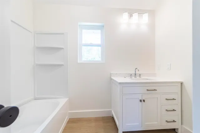 a bathroom with a bathtub sink vanity and mirror