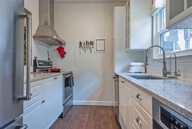 a kitchen with granite countertop a sink cabinets and stainless steel appliances