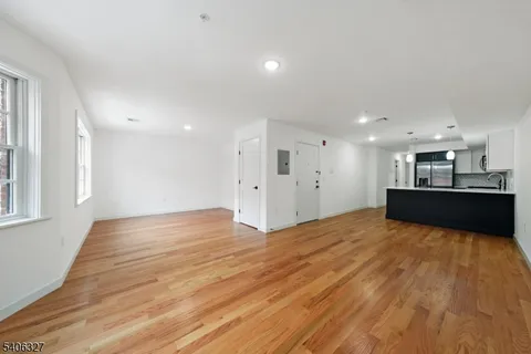 a view of kitchen and empty room with wooden floor