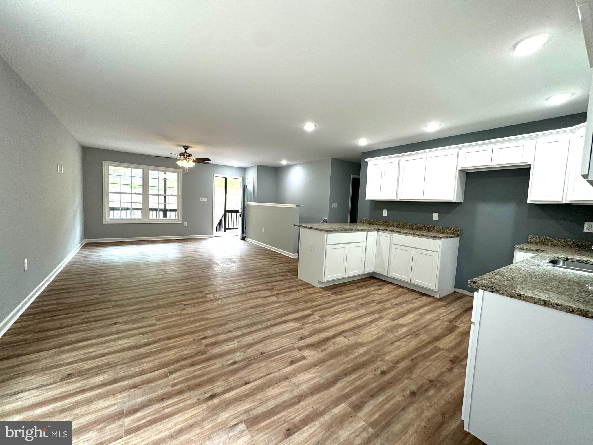 88 Thompson Mill Road Front Royal, VA 22630 - Photo 23 of 59 a large white kitchen with kitchen island a sink wooden floor and a refrigerator