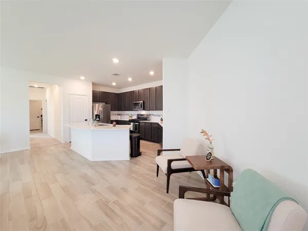 a view of kitchen with stainless steel appliances kitchen island a stove a refrigerator a sink and a oven with wooden floor