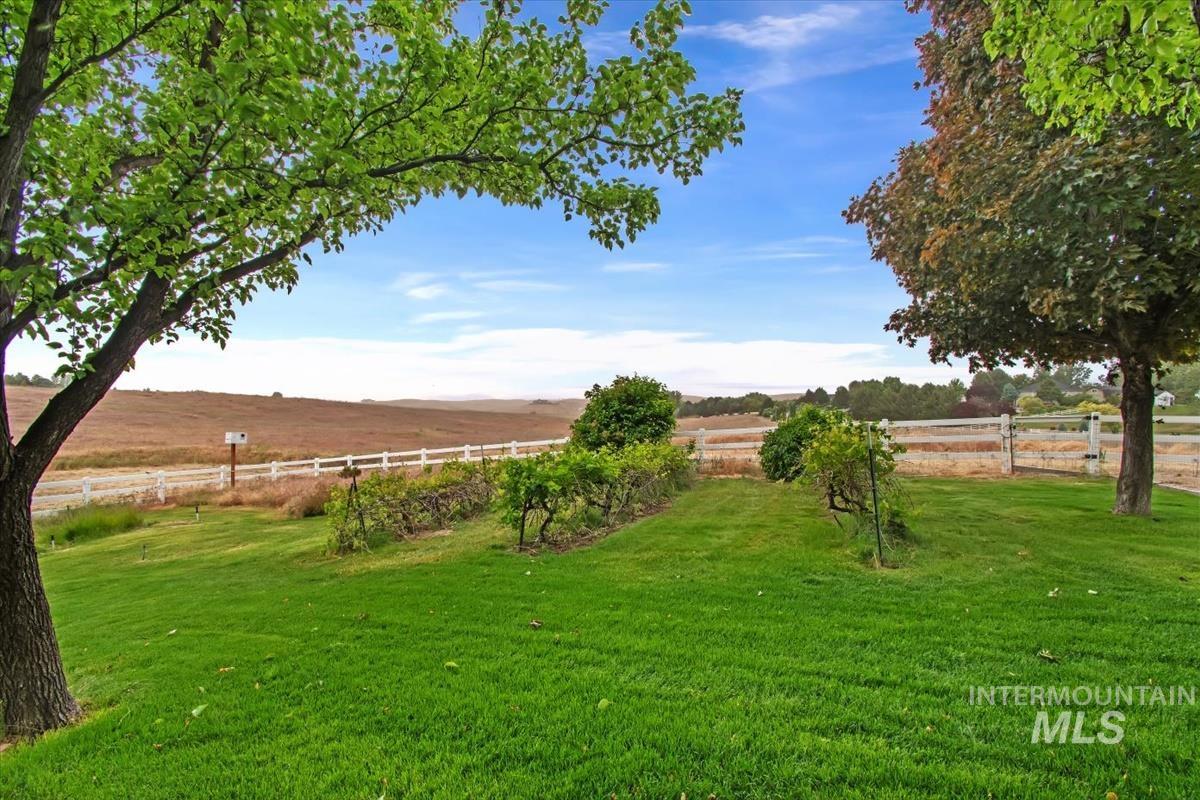 10462 West Lanktree Gulch Road Star, ID 83669 - Photo 39 of 48 Expansive green lawn framed by mature trees, featuring a white fence bordering open fields