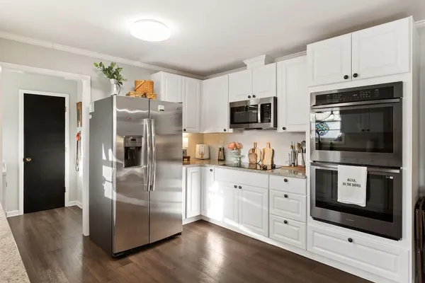 a kitchen with cabinets stainless steel appliances and wooden floor